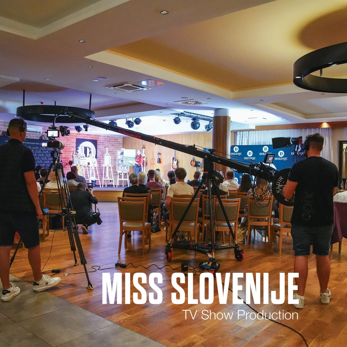 Snemalna žirafa in kamera med snemanjem dogodka v dvorani s publiko.