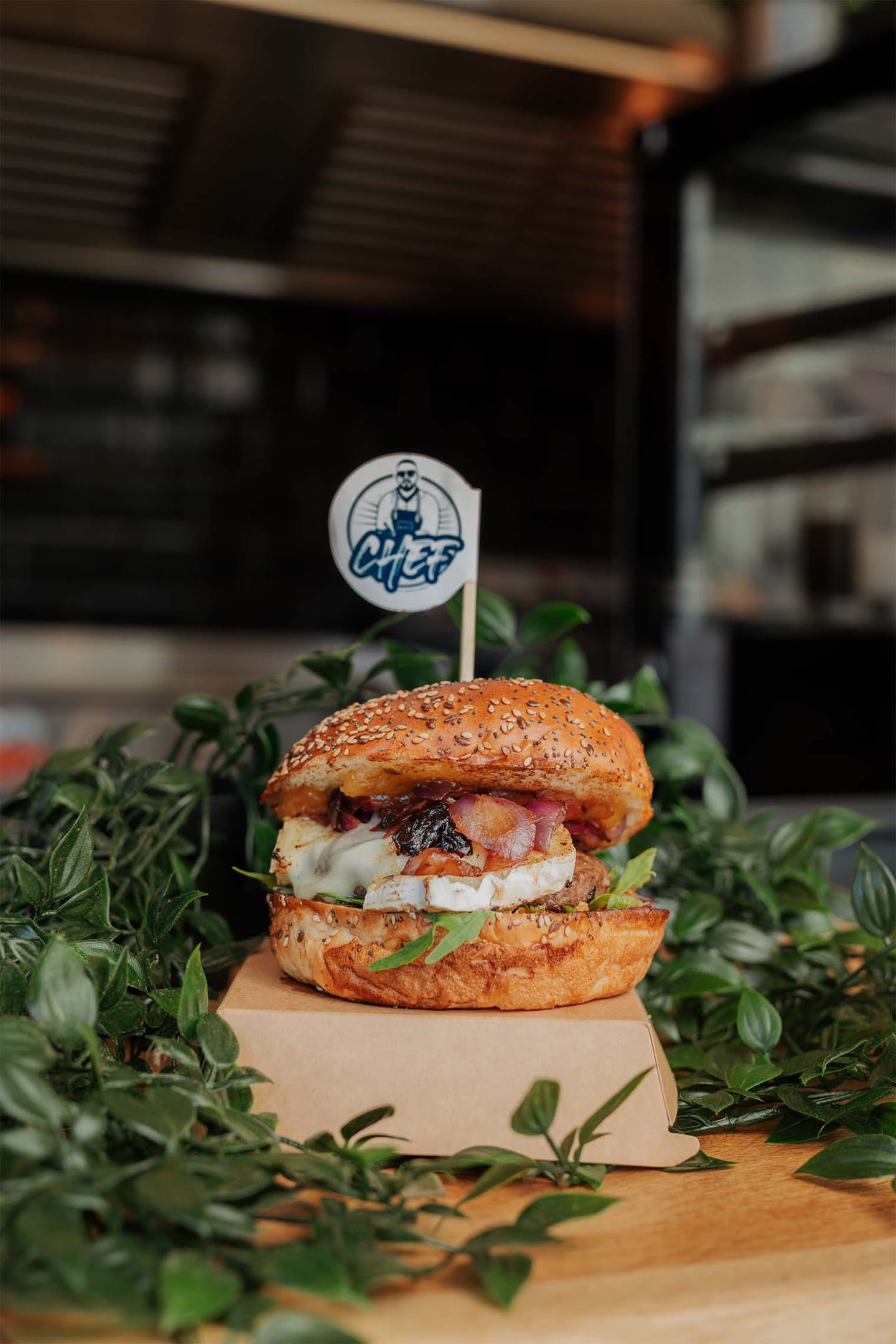 Hamburger s sirom in slanino na sezamovi žemlji, obdan z zelenjem